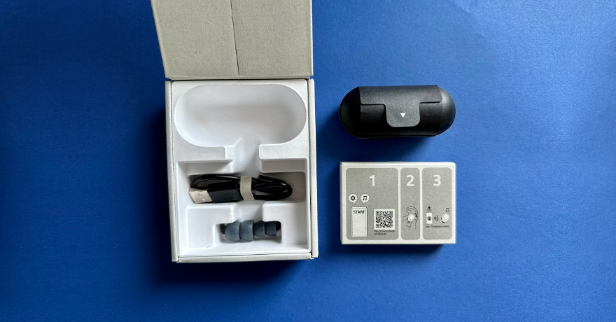 Aufgeklappte Box zeigt Standardzubehör: 3 Paar Silikonaufsätze (Größe M vormontiert), Mini-USB-C-Ladekabel.
